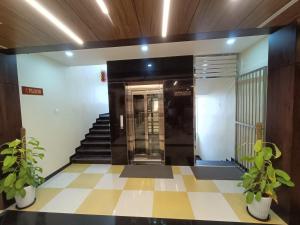 an elevator in a building with two potted plants at Sri Aswin Grand in Nāmakkal