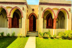 an old building with arched doors and a grass yard at Oriental house in Luxor