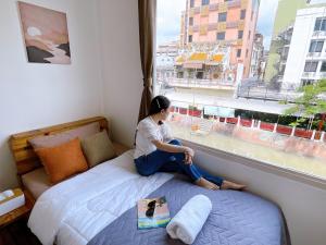 a woman sitting on a bed looking out of a window at Lively and cozy canal house ,Entire house in Bangkok