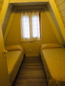 Duas camas num pequeno quarto com uma janela em Cabañas Chapelco em San Martín de los Andes