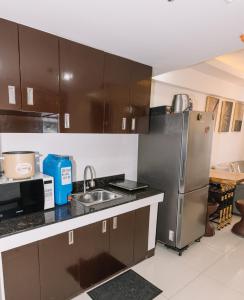 La cuisine est équipée de placards bruns et d'un réfrigérateur en acier inoxydable. dans l'établissement Gonzales Transient House, à Baguio