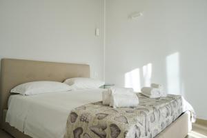 Un dormitorio con una gran cama blanca con toallas. en Il Trogolo, en Matera