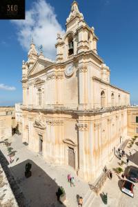 イムディーナにあるPalazzo 16th Century Mdina, opposite St Paul's Cathedral by 360 Estatesの時計塔のある大きな建物