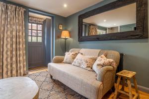 a living room with a couch and a mirror at Tipple Cottage in Peasenhall
