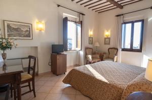 una camera con letto, tavolo e scrivania di Hotel Umbra ad Assisi