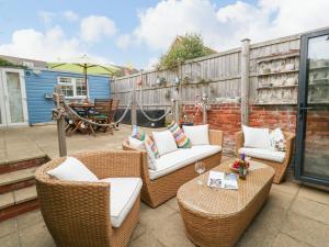 a patio with wicker chairs and tables and an umbrella at Sandy Toes in Weymouth