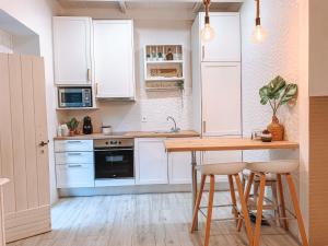 ポルトにあるDouro Rural Suiteの白いキャビネット、テーブル、スツール付きのキッチンが備わります。