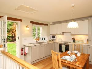 a kitchen with white cabinets and a wooden table at Mill Cottage in Upwey