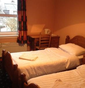 a bedroom with two beds and a desk and a window at Twin Lions Hotel in Edinburgh