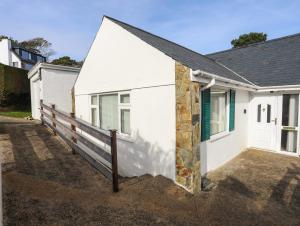 a white house with a fence next to it at 14 Cae Pin in Pwllheli