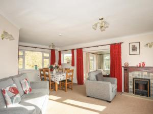 a living room with a fireplace and a table and chairs at 14 Cae Pin in Pwllheli