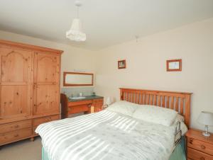 a bedroom with a bed and a dresser and a mirror at 14 Cae Pin in Pwllheli