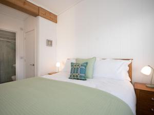 a bedroom with a green and white bed with two lamps at Murmur y Coed in Llanfairpwllgwyngyll