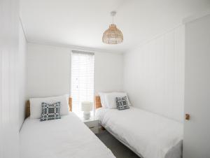 two beds in a room with white walls and a window at Galwad y Mor in Llanfairpwllgwyngyll