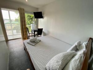 Schlafzimmer mit einem Bett, einem Tisch und einem Fenster in der Unterkunft Victoria's Bed & Breakfast in Puerto Galera