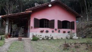 uma casa cor-de-rosa com janelas e vasos de plantas em Sitio Aguá Santa em Itapeva