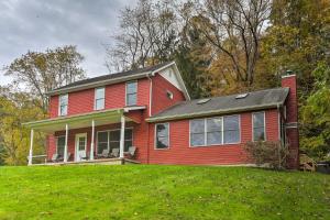 a red house on top of a grassy hill at Sugar Grove Escape with Hot Tub and Grill! in Sugar Grove