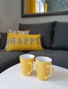 two yellow coffee cups sitting on a table with a couch at Sky apartments FREE PARKING in Wrocław