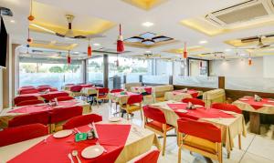 un restaurante con mesas rojas y sillas en una habitación en The Tripti Hotel & Banquets, en Indore