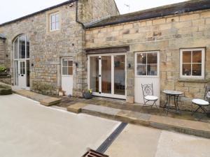 a stone house with a table and chairs outside at Mosscarr Barn in Harrogate