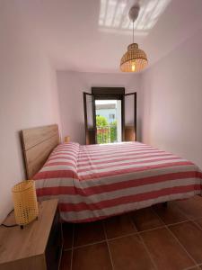 um quarto com uma cama com um cobertor listrado vermelho e branco em La Casa del Muro em El Bosque