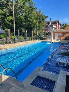 a large swimming pool with blue water and chairs at Pousada Acqua Infinity PISCINA CLIMATIZADA PÉ NA AREIA in Bertioga