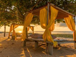 a bed on the beach with the sunset in the background at Hotel Marina Porto Abrolhos in Caravelas