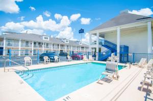 a swimming pool with chairs and a hotel at Baymont by Wyndham Tuscaloosa in Tuscaloosa