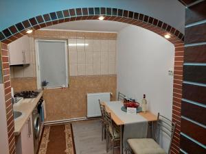 einen Torbogen in einer Küche mit einem Waschbecken und einem Tisch in der Unterkunft 1st Apartment in Nehoiu