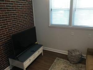 uma sala de estar com uma televisão de ecrã plano e uma parede de tijolos em Newly Renovated Historic Home Near Park Circle em Charleston