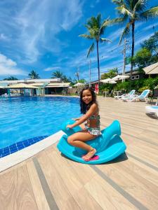 Porto Mar Hotel في بورتو سيغورو: بنت صغيرة جالسة على طوف بجانب مسبح