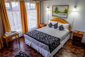 a hotel room with a bed and two windows at Hostal Alcázar in Puerto Natales