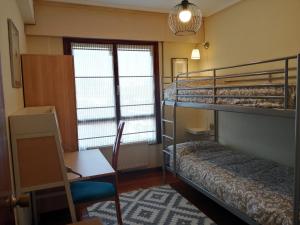 Zimmer mit 2 Etagenbetten, einem Tisch und einem Schreibtisch in der Unterkunft Andramari Tourist Home Parking& wifi in Amorebieta-Etxano