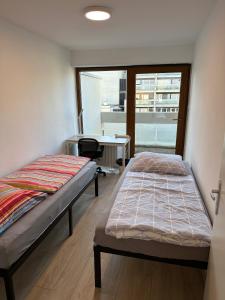2 Betten in einem Zimmer mit einem Schreibtisch und einem Fenster in der Unterkunft Nice, big and central apartment with 2 balconies in Karlsruhe