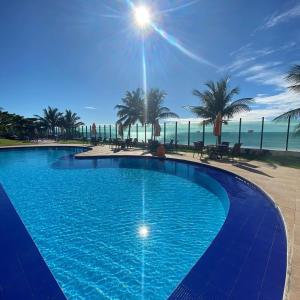 uma grande piscina azul ao lado de uma praia em Flat Tabatinga Nord, vista para o mar em Conde