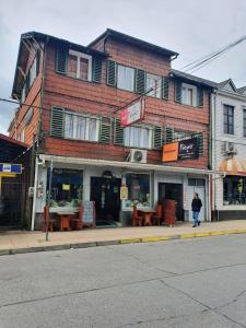 un bâtiment situé dans une rue avec des tables devant elle dans l'établissement Hostal Papo, à Osorno