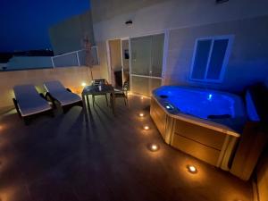 a room with a tub and a table and chairs at Cittadella View Penthouse with Jacuzzi in Victoria