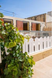 a white picket fence in front of a building at Bliss Boutique Living in Xagħra