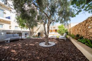 un patio con un árbol y dos sofás y un edificio en Bliss Boutique Living en Xagħra