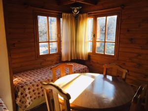 a dining room with a table and chairs and windows at Cabañas Chapelco in San Martín de los Andes