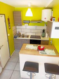 a small kitchen with a counter and yellow walls at Agréable studio dans le centre historique in La Ferté-Saint-Aubin