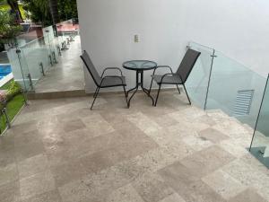 - une terrasse avec 2 chaises et une table à l'étage dans l'établissement Hotel fresno Xochitepec, à Chiconcuac