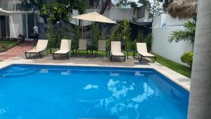 una piscina con sillas y sombrilla en Hotel fresno Xochitepec, en Chiconcuac