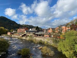 a river in a town with buildings and houses at Abbey Cottage in Llangollen
