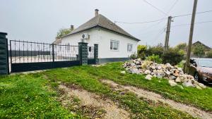 a white house with a fence and a pile of rocks at Csatangoló Lovas Vendégház 