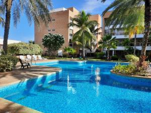 una piscina frente a un edificio con palmeras en ¡Hermoso Apartamento en Loma Real! en Porlamar