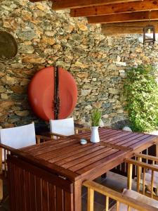 a wooden table and chairs in front of a stone wall at Casa das Quintas in Quinta das Quebradas