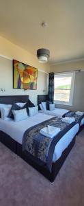 2 große Betten in einem Schlafzimmer mit einem großen Fenster in der Unterkunft Alexandra Hotel in Eastbourne
