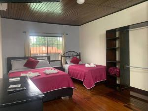 um quarto com 2 camas com lençóis vermelhos e uma janela em Alojamiento entero 1 km Juan Santamaría Airport em Alajuela