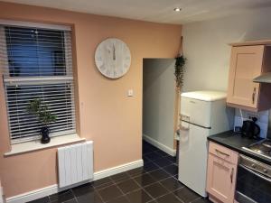 uma cozinha com um relógio na parede e um frigorífico em 'Afton' at stayBOOM em Lancaster